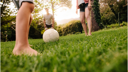 Three people play soccer on a lawn