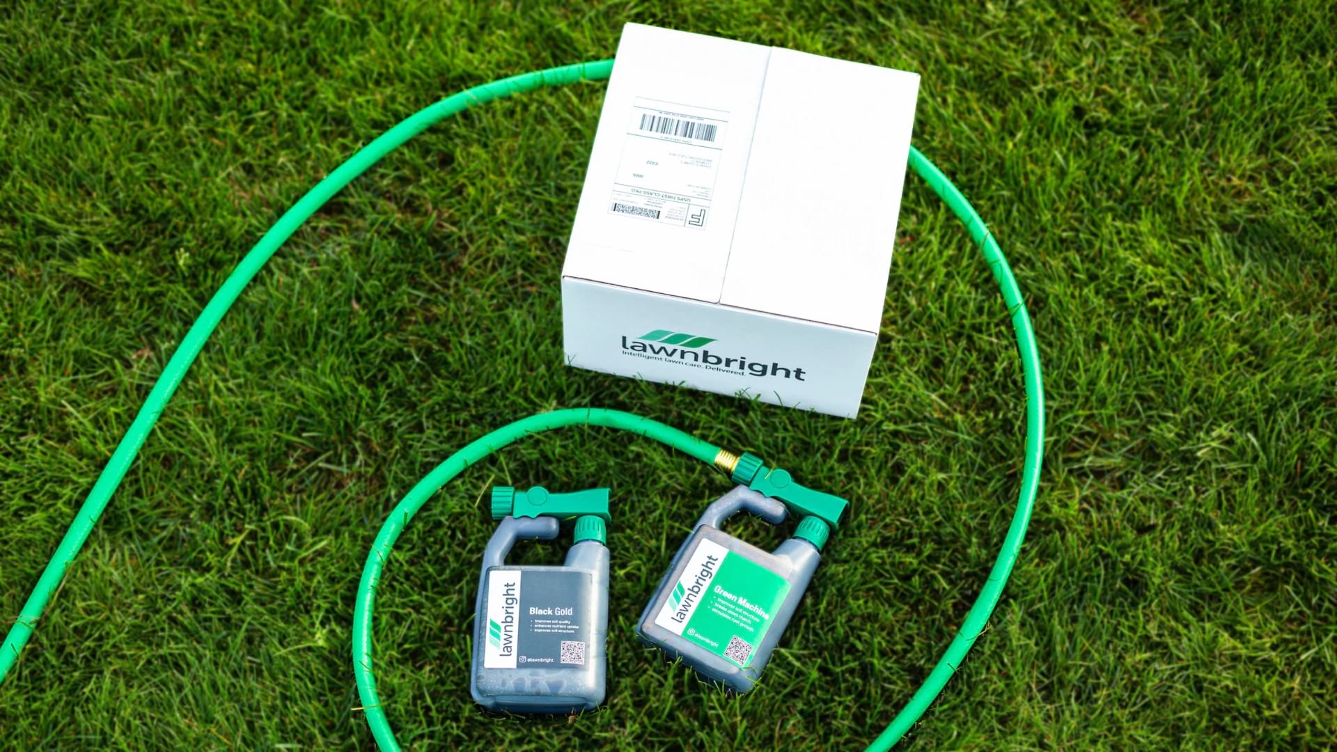 A shipping box, hose, and Lawnbright bottles displayed on green, healthy grass.
