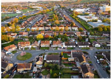 Aerial view of a suburban area with houses, roads, and green spaces.