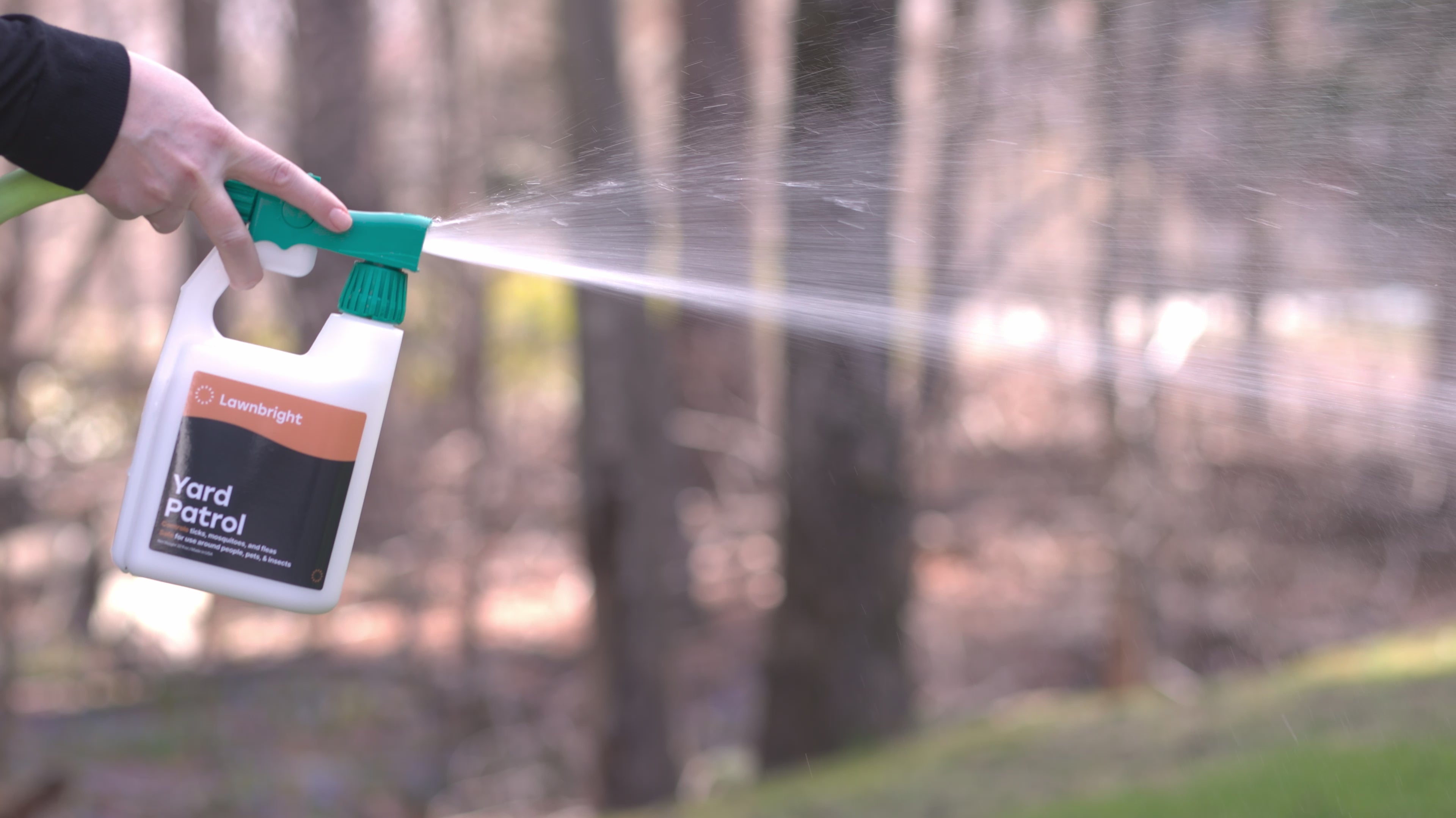 Load video: A woman sprays Yard Patrol near the perimeter of a lawn.
